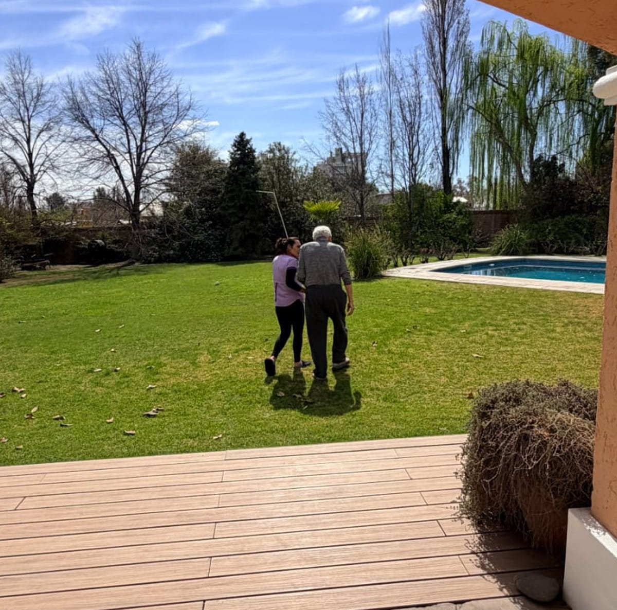 Persona mayor acompañada durante un paseo por el jardín de la residencia