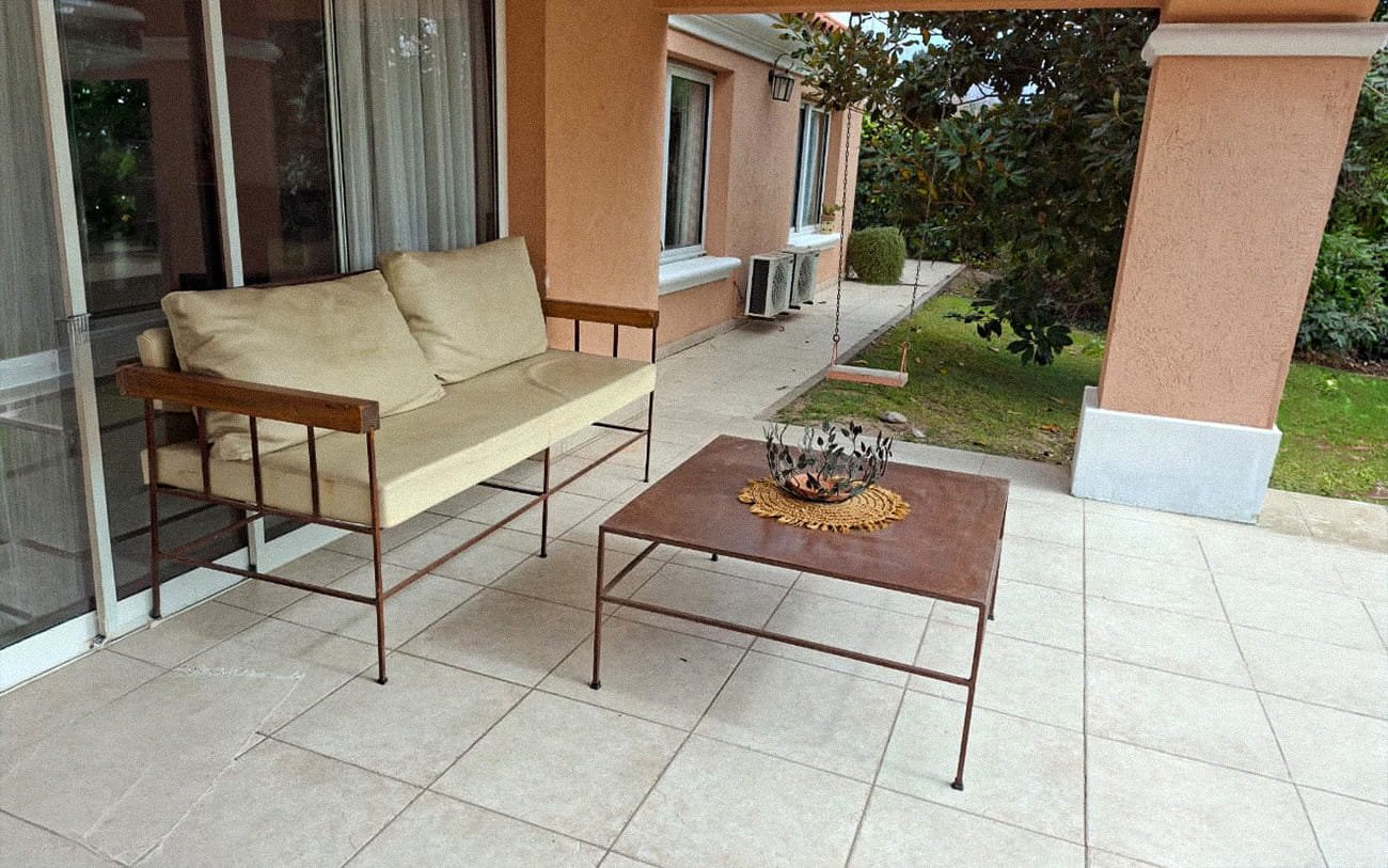 Galería exterior con sillón y vista al jardín de la residencia Pewen