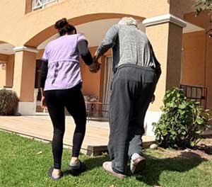 Persona mayor acompañada por una cuidadora durante una caminata