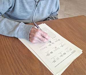 Persona mayor realizando una actividad de escritura en una mesa